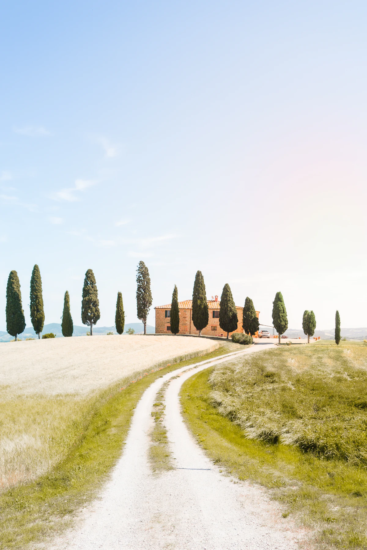 Tuscan stone farmhouse framed by cypress trees in the Val d'Orcia countryside
